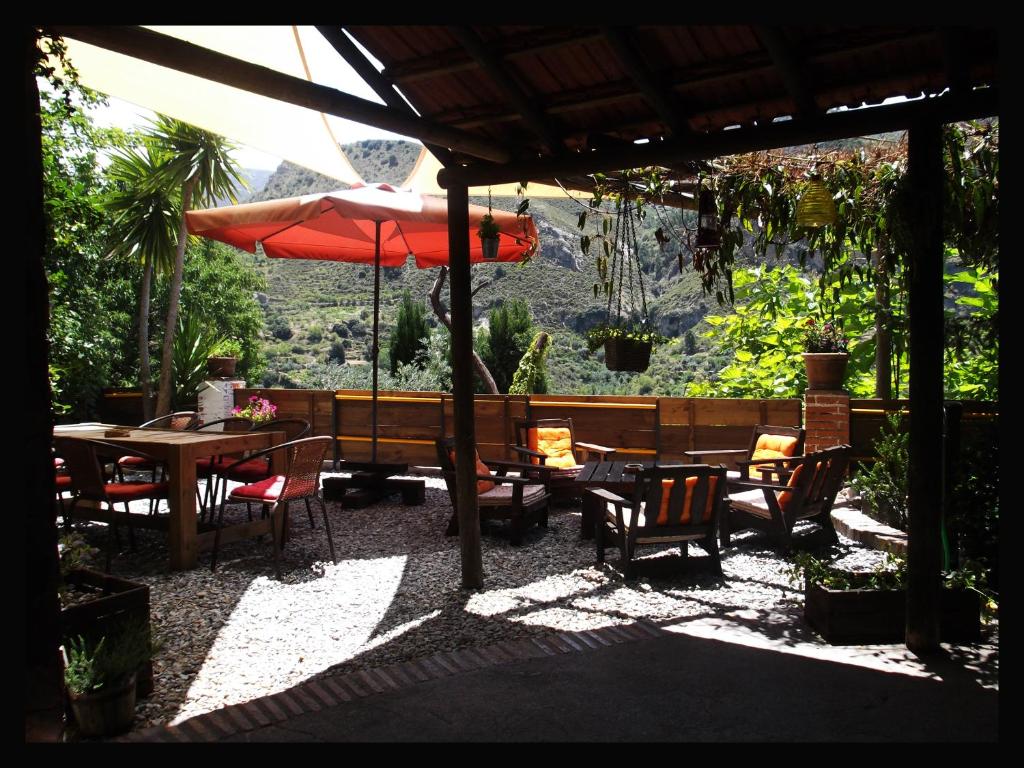 Quéntar丰达路西亚住宿加早餐旅馆的庭院配有桌椅和遮阳伞。