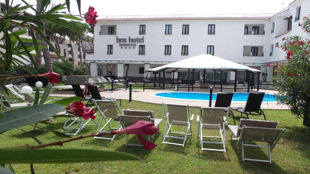 巴亚多米吉亚BNS Hotel Francisco的一组椅子坐在游泳池旁的草地上