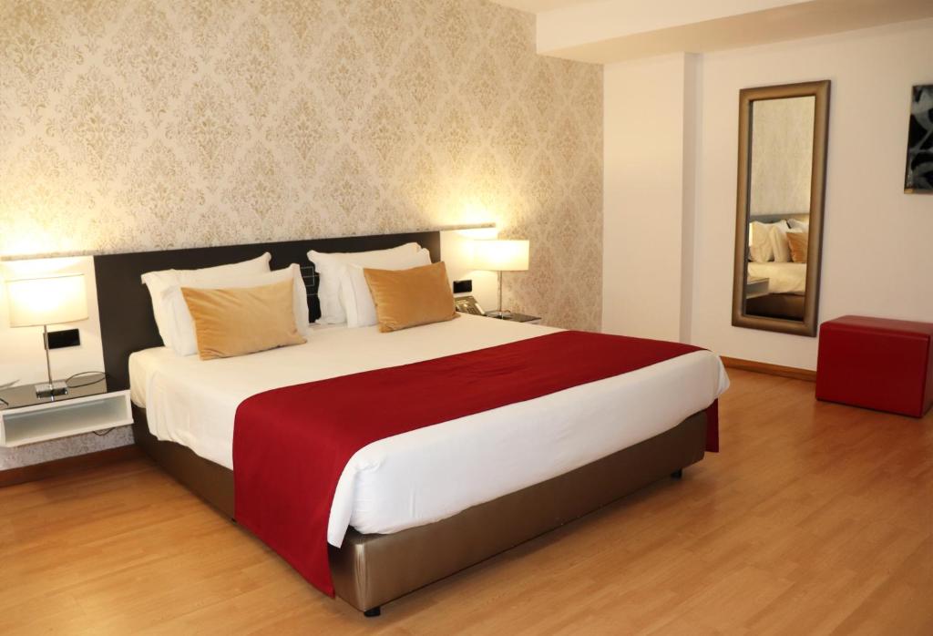 马托西纽什阿玛迪奥城市酒店 的一间卧室配有一张大床和镜子