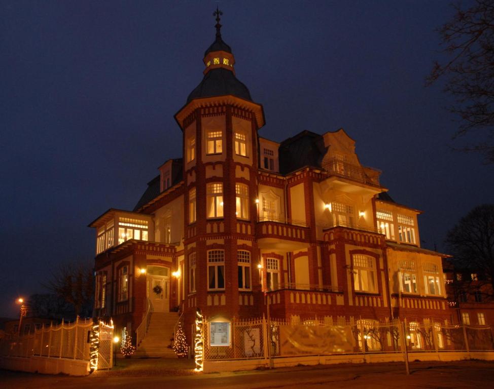 米兹多洛杰斯特拉马里斯别墅公寓式酒店的一座在晚上设有钟楼的大型建筑