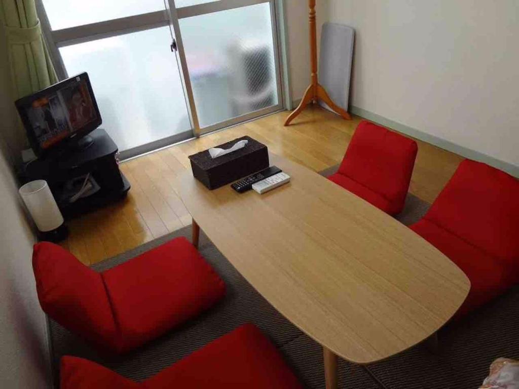 福冈Vintage III - Vacation STAY 14906的配有木桌和红色椅子的房间
