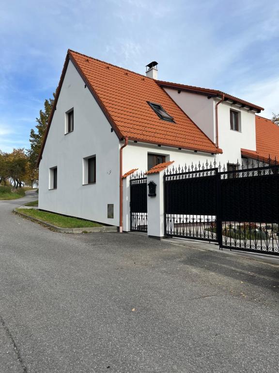 捷克克鲁姆洛夫Apartmány U Procházků的白色的房子,有橙色的屋顶和黑色的围栏