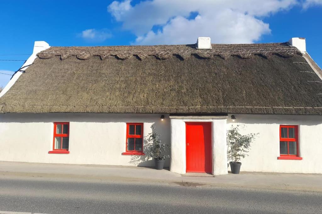 RushLuxury 300yr old Irish thatch cottage close to sea的白色的房子,有红色的门和茅草屋顶