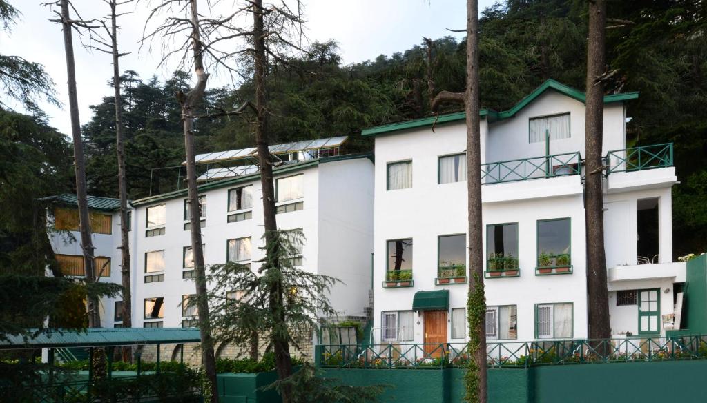 西姆拉西姆拉蜜月酒店的前面有树木的白色建筑