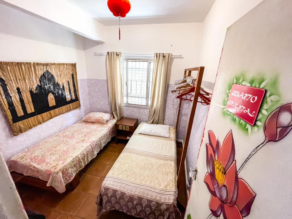 维多利亚Toca da Mona Roots Hostel的一间设有两张床的客房,墙上有标志