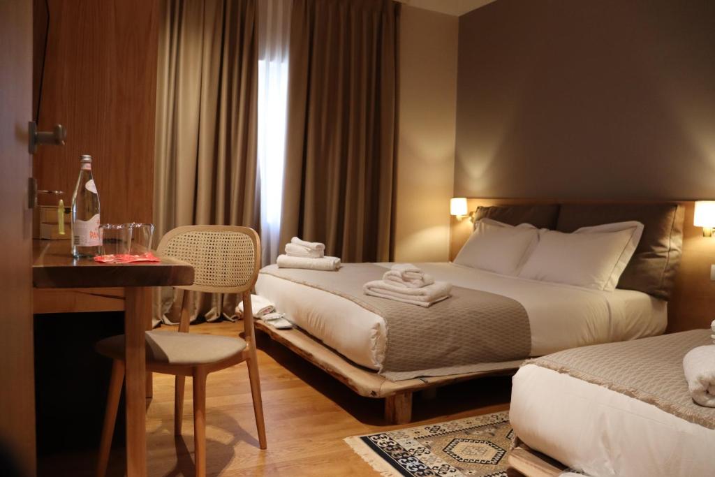 戈里察Velar Hotel Boutique的酒店客房配有两张床、一张桌子和一张书桌