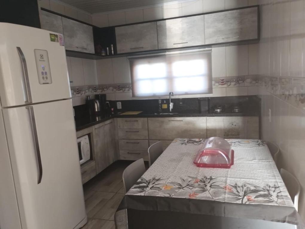 因贝Casa em imbé的厨房配有桌子和白色冰箱。
