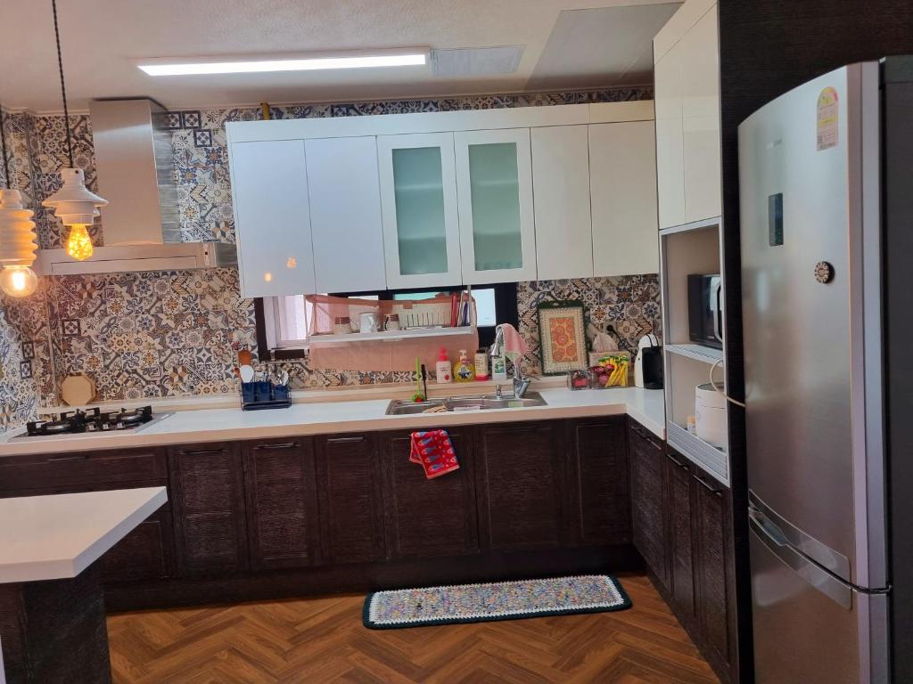 安东市Food House的厨房配有白色橱柜和不锈钢冰箱