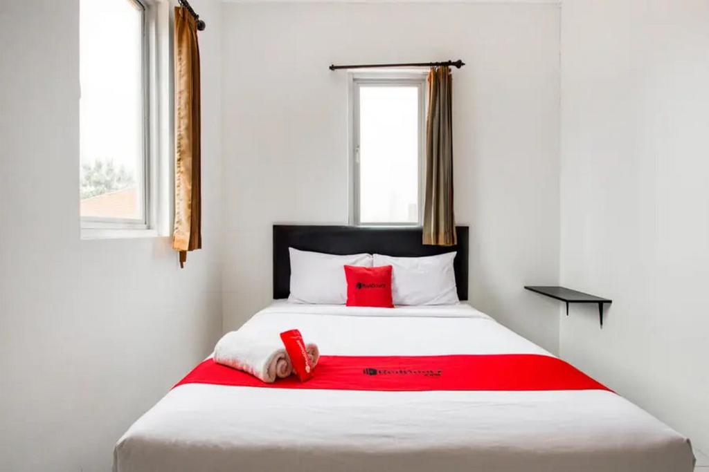 WatulawangRedDoorz Plus near Galaxy Mall的卧室配有带红色枕头的大型白色床