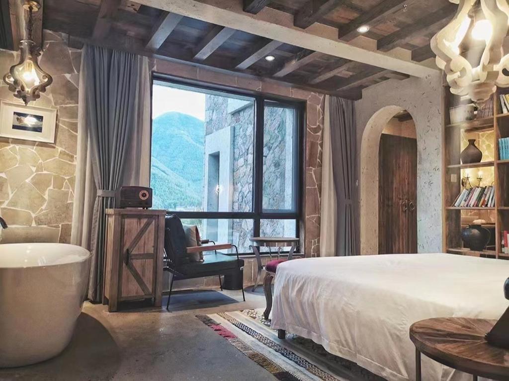 德清莫干·听山酒店的一间卧室配有一张床、一把椅子和一个大窗户