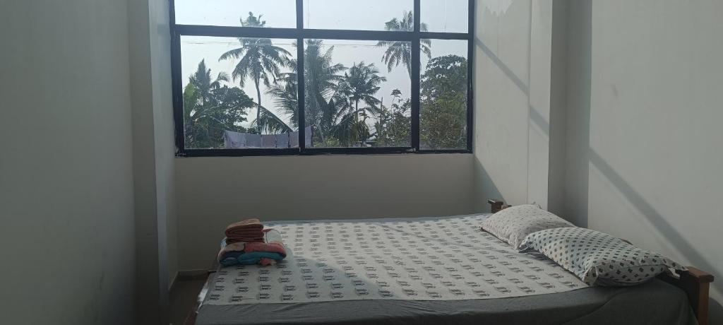 阿勒皮Beach vibe hostel的窗户客房内的一张床位