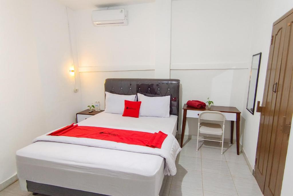 班达楠榜RedDoorz at Kubu Selem Lampung的一间卧室配有一张白色的床铺、红色的床单和一张书桌