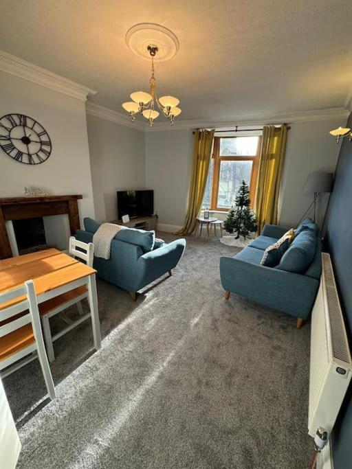 MytholmroydLovely home with a river view的客厅配有2张蓝色的沙发和1张桌子