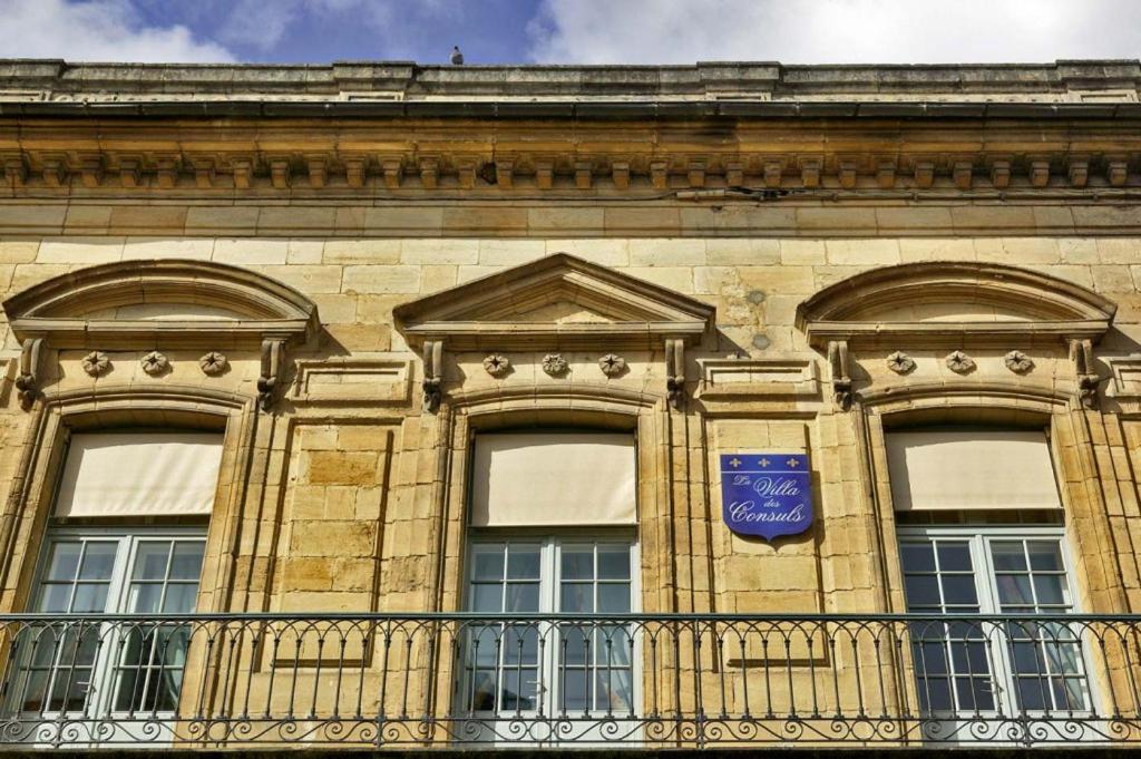 萨尔拉拉卡内达La Villa des Consuls - Gîte de tourisme de charme的一座带窗户的建筑,上面有蓝色的标志