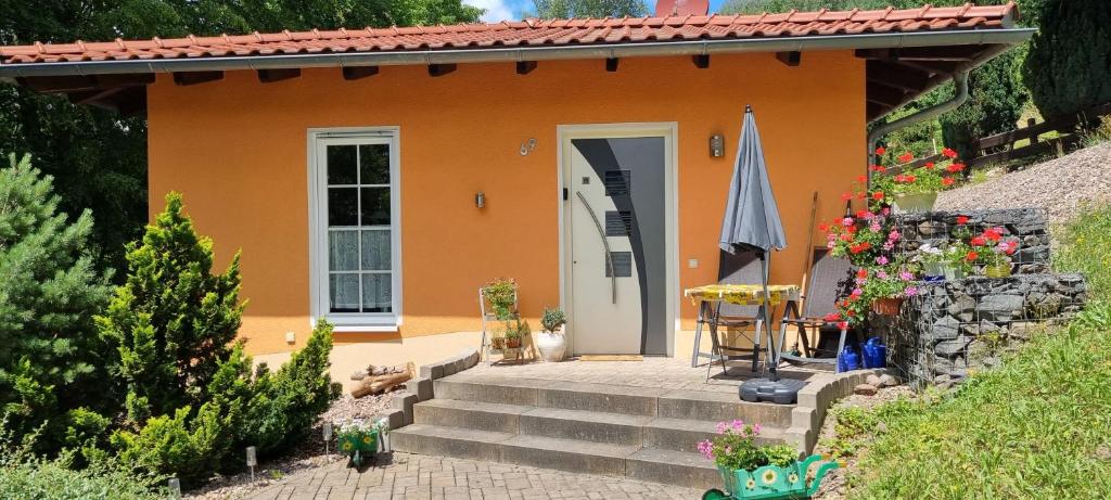 索内贝格Ferienhaus - Bungalow的一座带楼梯和庭院的橙色小房子