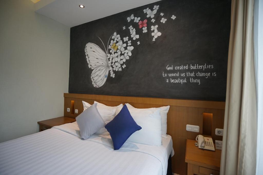 马格朗斯睿提马格朗酒店的一间卧室配有一张床上,墙上挂着蝴蝶画