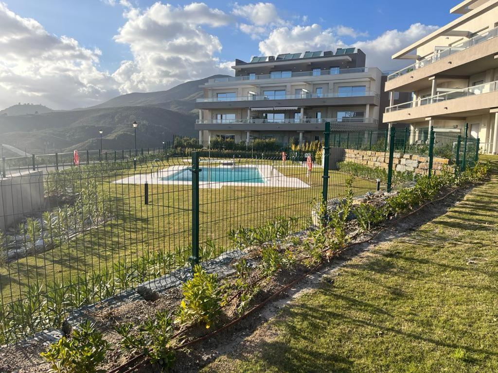 马拉加La Cala de Mijas Apartment的建筑前带游泳池的围栏