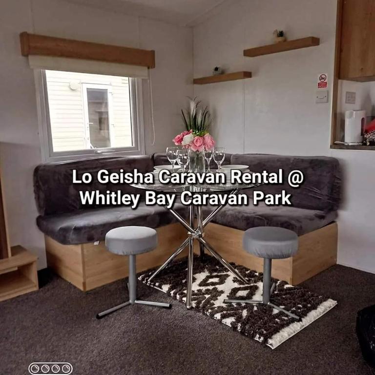 惠特利湾Lo Geisha Caravan Rental at Whitley Bay Caravan Park的客厅配有黑色沙发和2张凳子