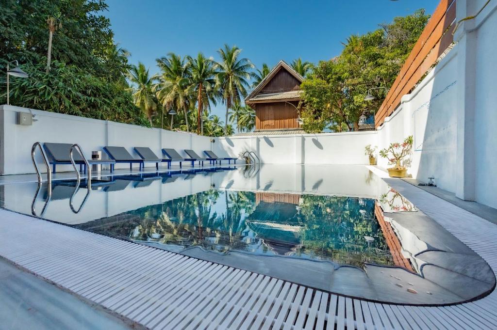 琅勃拉邦LuangPrabang Center Hotel的一座建筑物边带椅子的游泳池