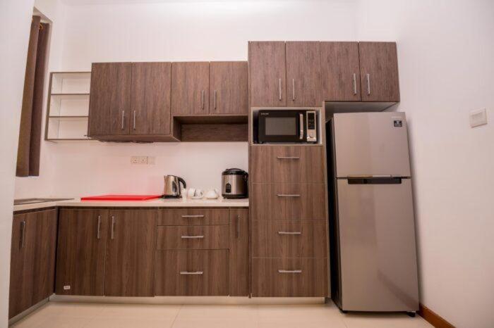 康提Kings Hantana的厨房配有木制橱柜和冰箱。