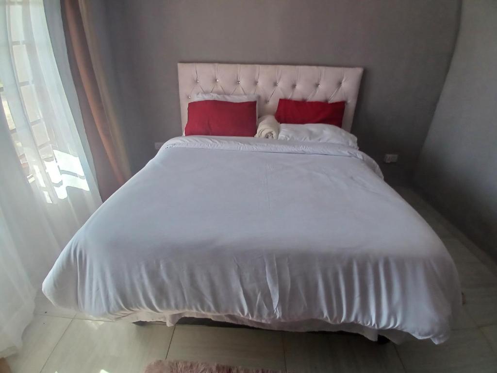 马翁Partulaka Rest Inn的一张带两个红色枕头的白色床