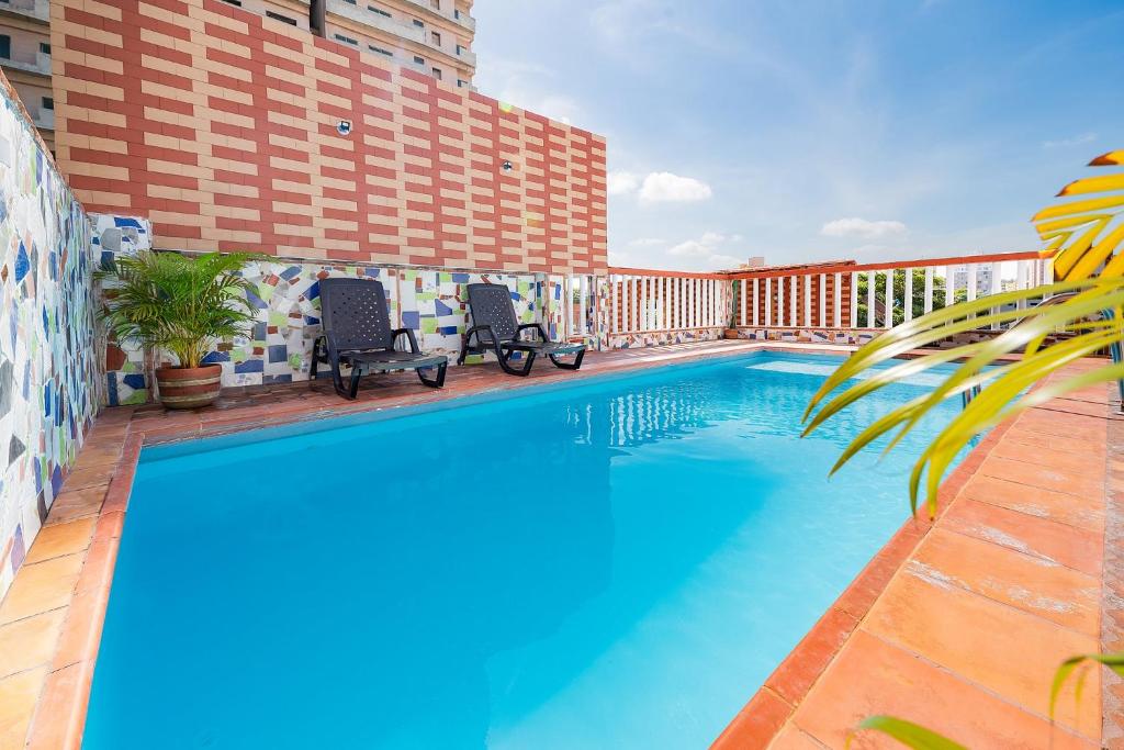 巴兰基亚Villa Santos Apartaestudios的旁边设有两把椅子的酒店游泳池