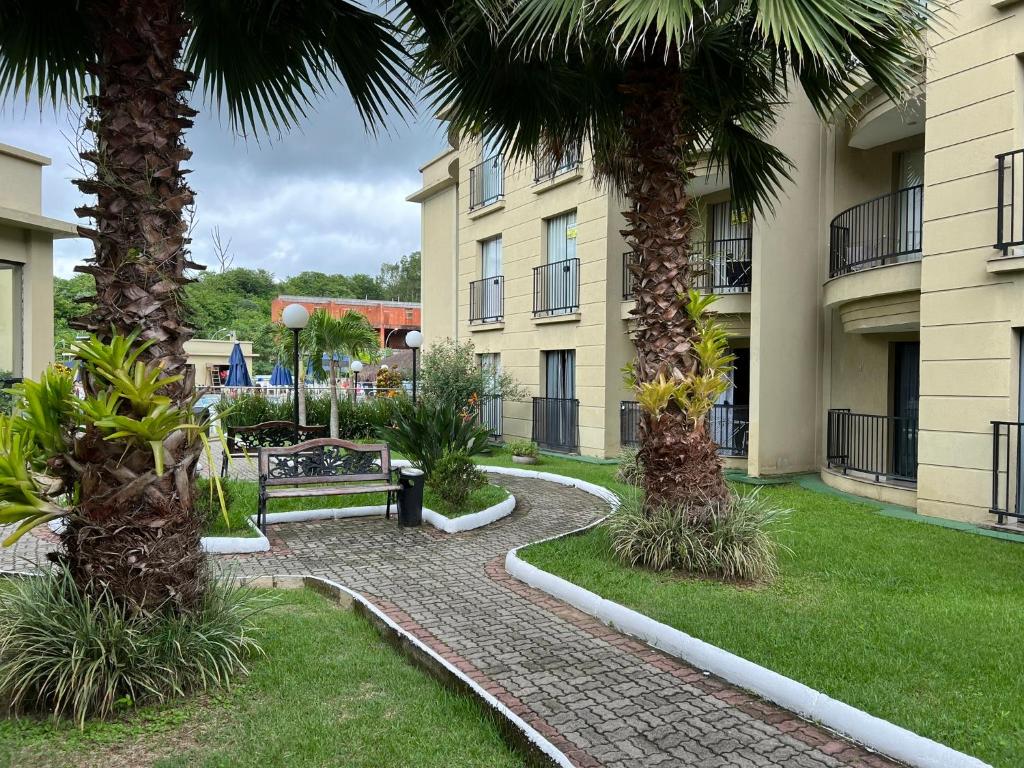 皮拉伊河畔巴拉Aldeia das Águas Park Resort - Quartier - Flat B102的两栋公寓楼之间的走道,两栋公寓楼之间种有棕榈树