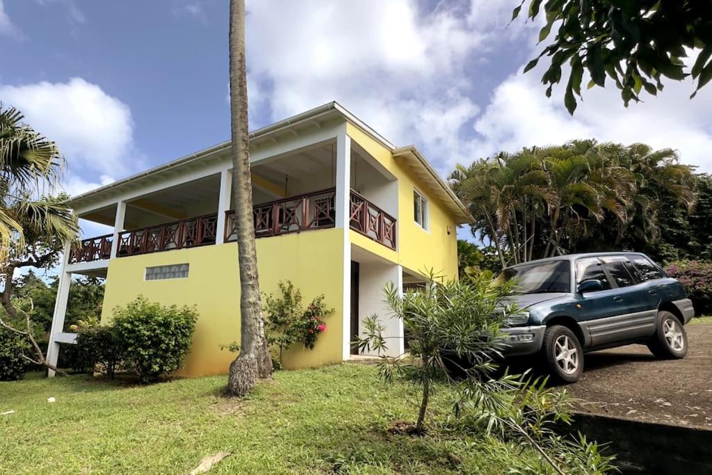 CalibishieLaCaye - Home in Creole的停在黄色房子前面的汽车
