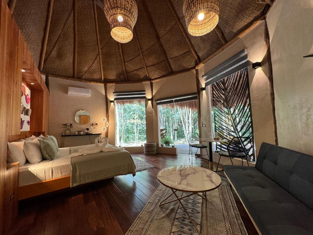 斯普希尔Casa Kaan Calakmul的一间卧室配有一张床、一张沙发和一张桌子