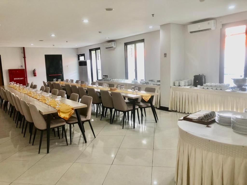 雅加达AZKA HOTEL Managed by Salak Hospitality的一间带桌椅的用餐室和一间酒吧