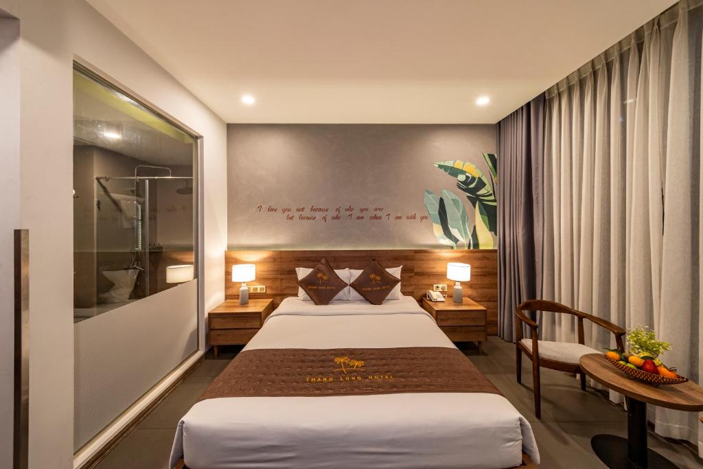 胡志明市Thanh Long Hotel - Tra Khuc的酒店客房,配有两张床、一张桌子和一把椅子