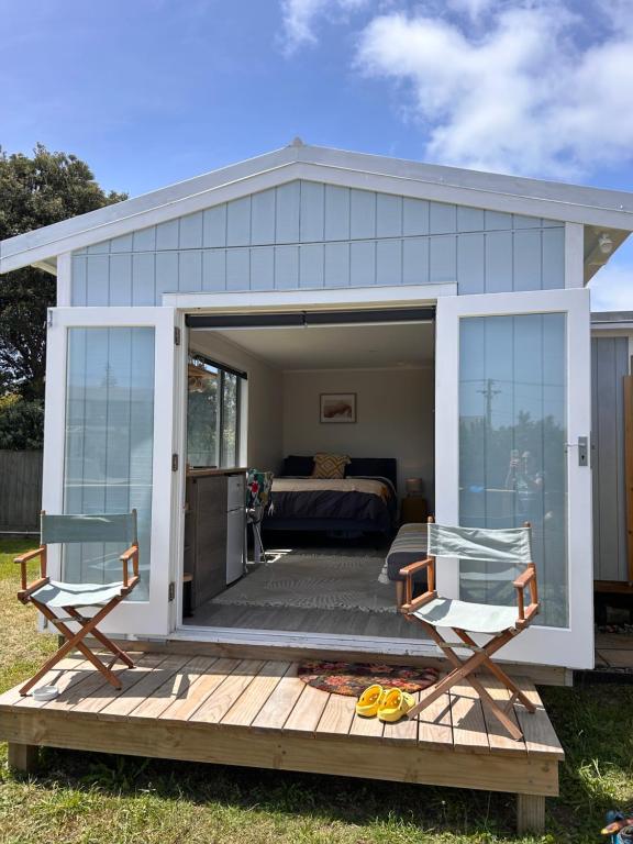 Otaki BeachKowhai Landing Beach Cabin的一间房间,甲板上配有一张床和两把椅子