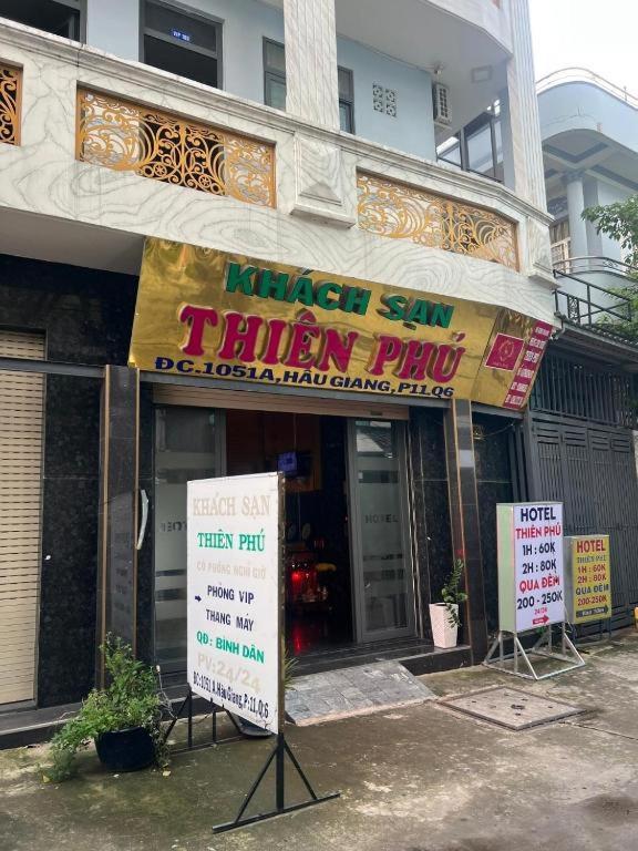 胡志明市Khách Sạn Thiên Phú的建筑前有标志的商店