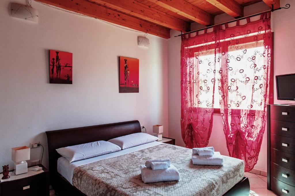 San SperateCasa Azzurra的一间卧室配有床和红色窗帘的窗户