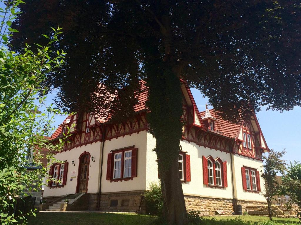 黑欣根Gästehaus "Unsere Stadtvilla"的一间大房子,有红色的窗户和一棵树
