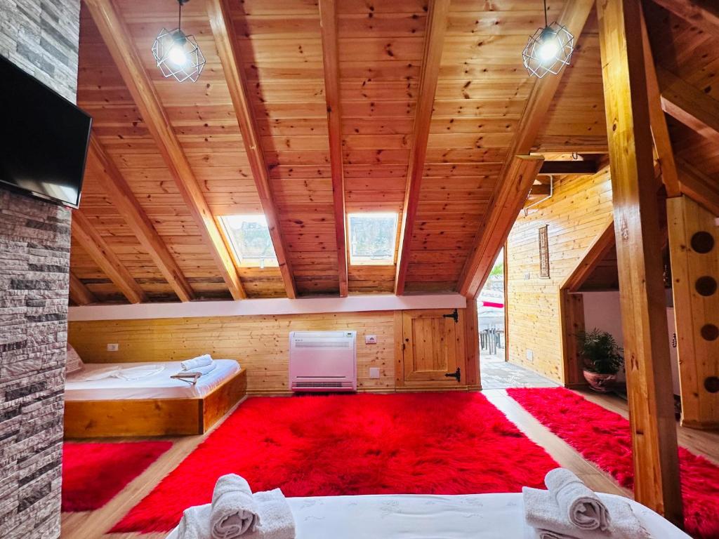 吉诺卡斯特Kore Guest House的阁楼间设有两张床和红色地毯。