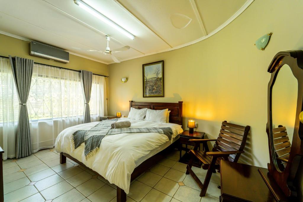 维多利亚瀑布Room in Villa - Zambezi Family Lodge - Lion Room的一间卧室配有一张床、一张桌子和一个窗户。