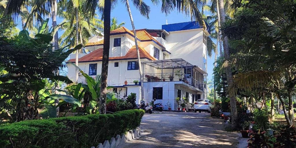 可瓦兰Indeevaram Apartments的街上的白色房子,种有棕榈树