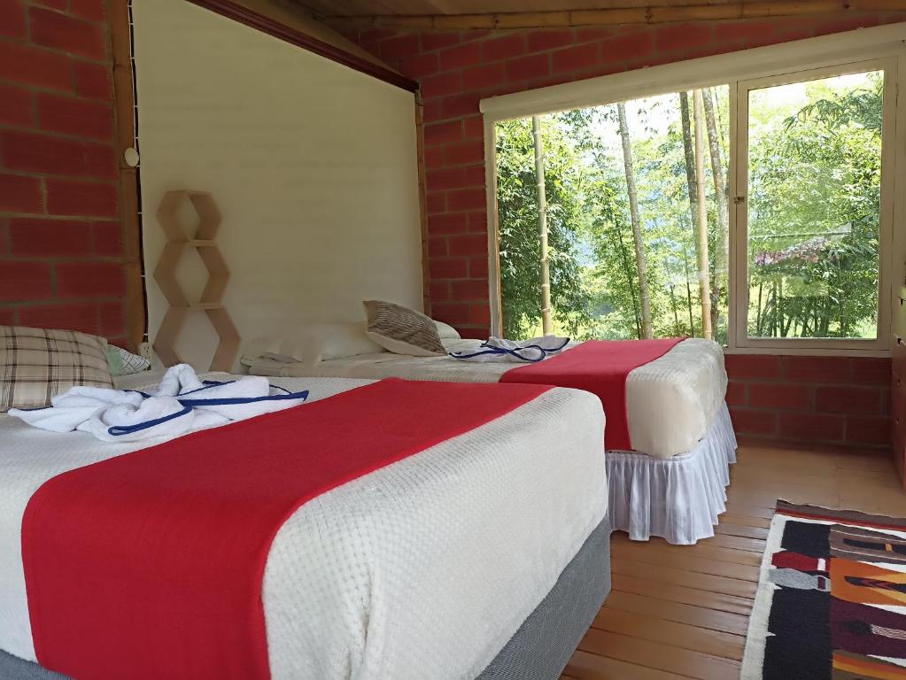 San Francisco de BorjaGreen Bamboo Lodge的客房内的两张床,配有红色和白色的毯子