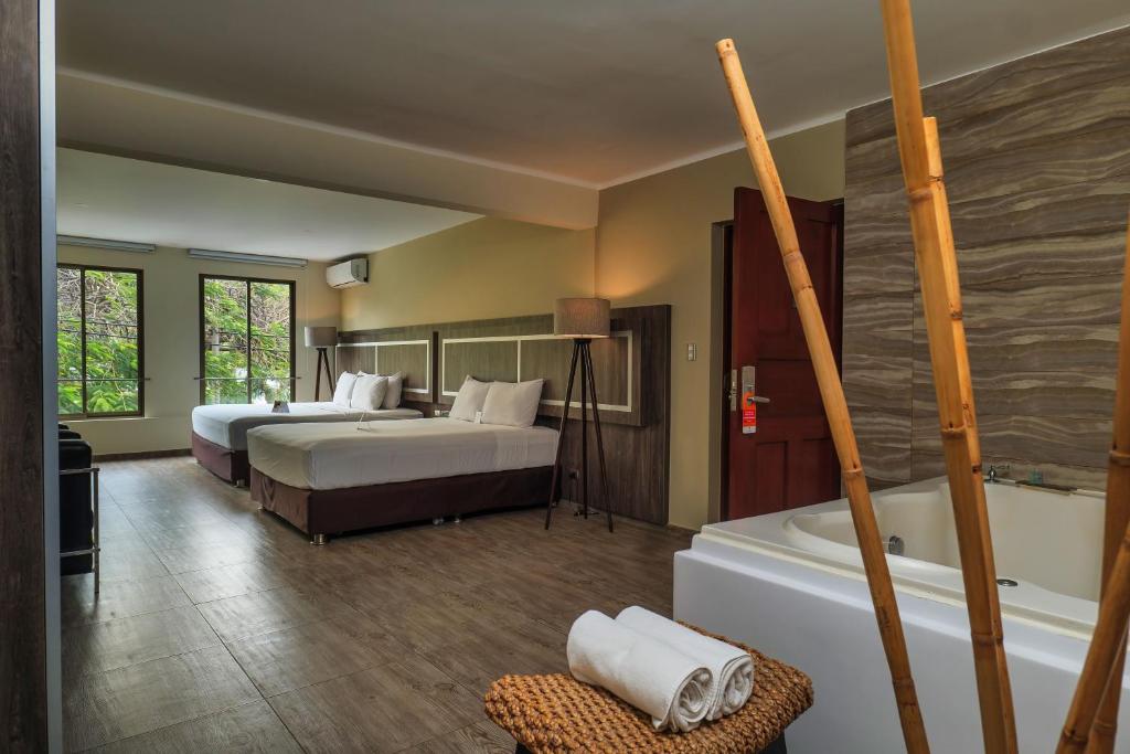 特鲁希略Rado Hotel - Quintanas的酒店客房设有两张床和浴缸。
