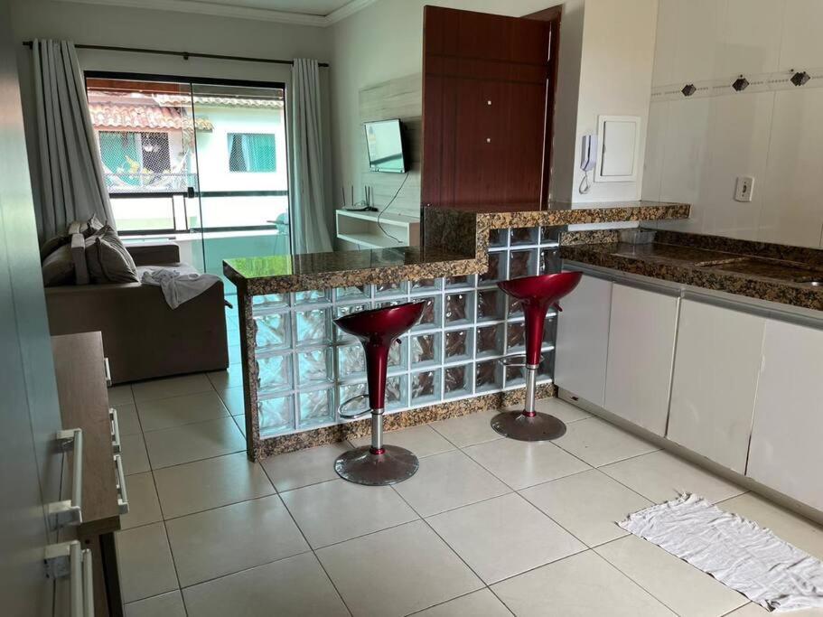 塞古罗港Apartamento mobiliado的厨房中间设有两个红色凳子