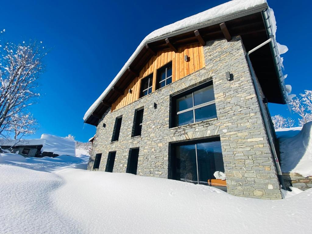 DoucyCHALET CONFIDENTIEL VALMOREL - Chalet de Haut de Gamme 4 étoiles 12 personnes的雪中覆盖的建筑