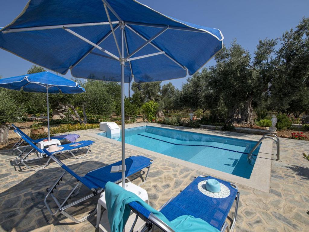 PangalochoriNice villa on small beautiful complex of 3 villas communal pool NW coast的一个带蓝伞和椅子的游泳池和一个游泳池