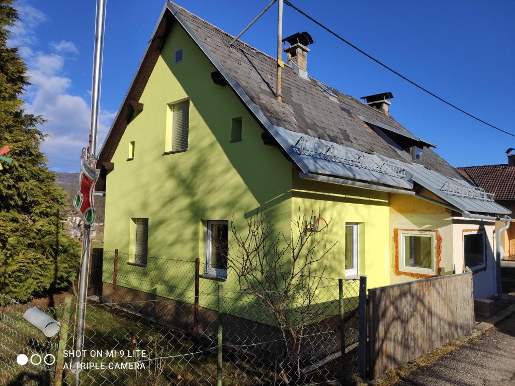 Feistritz im RosentalNice small house in beautiful Carinthia的黄色和绿色的房子,有黑色屋顶