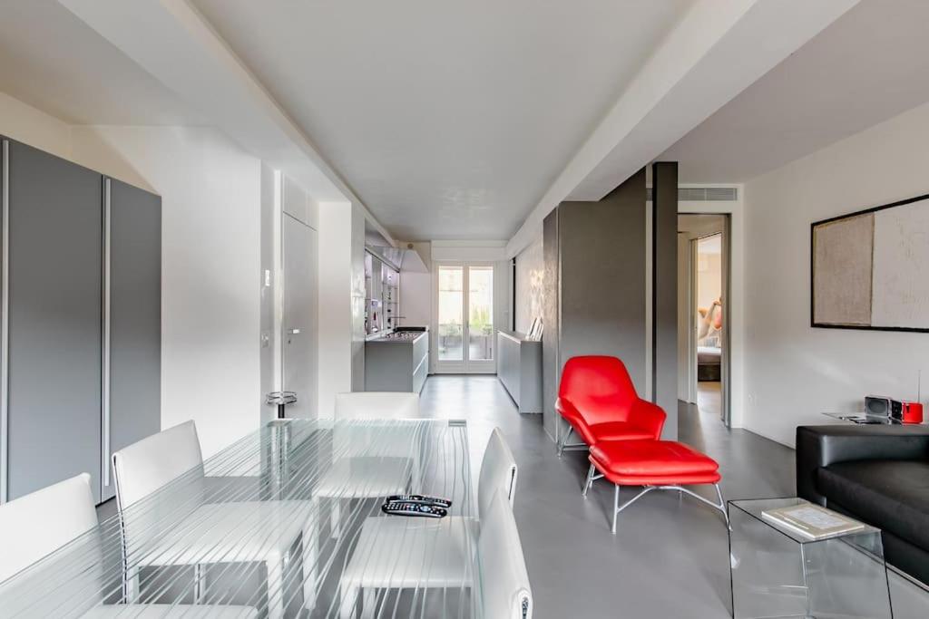 佩萨罗luxury apartment的客厅配有玻璃桌和红色椅子