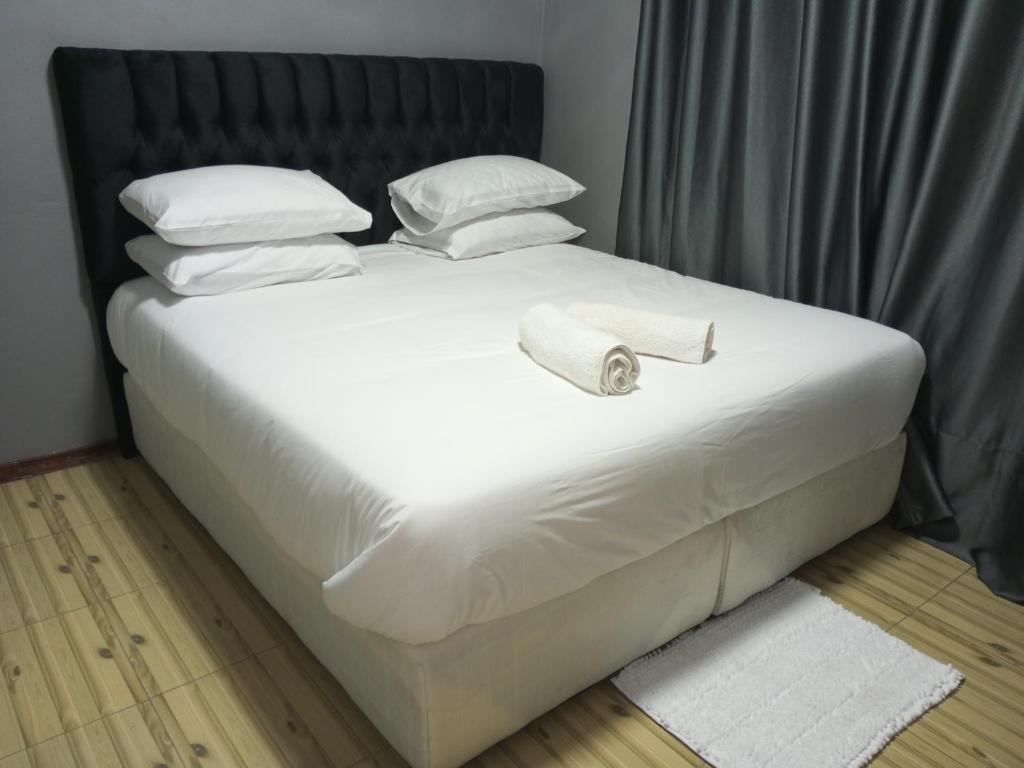 利文斯顿Ramachi apartments的一张带白色床单和枕头的床