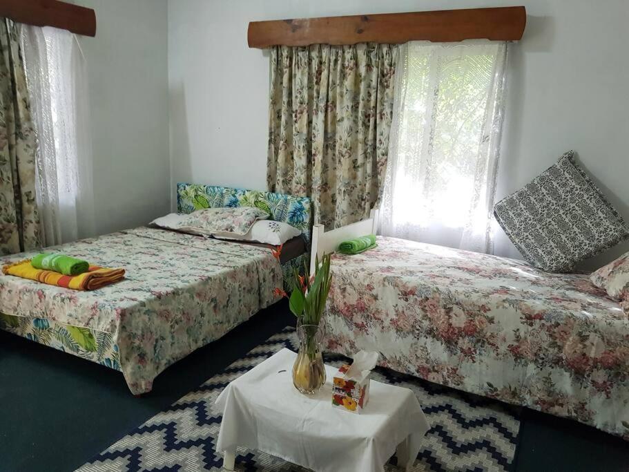 南迪Central Nadi - Lodge 2的一间卧室配有两张床和一张带花瓶的桌子