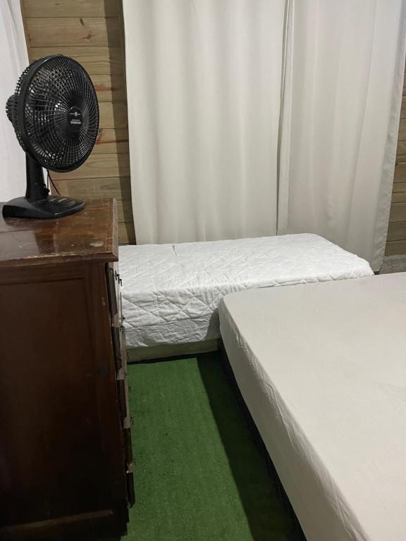 伊塔佩马KITNET cosntruçao quase já finalizada的客房设有两张床、一张书桌和风扇