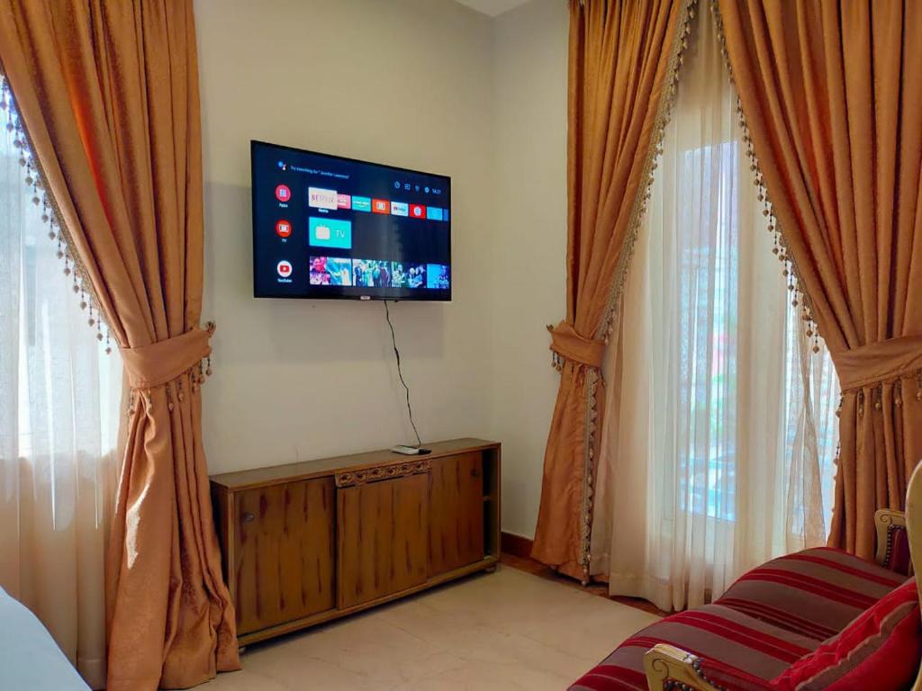 拉各斯Noble Villa Hotel的客厅配有平面电视和窗帘