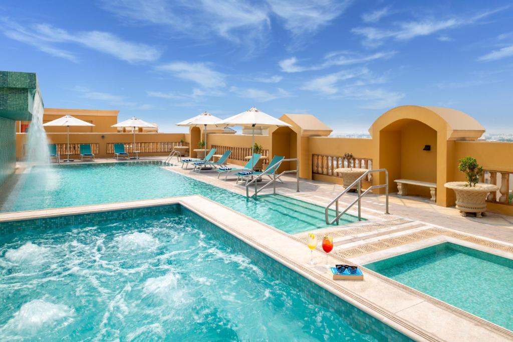 多哈Somerset Al Mansoura Doha的一个带椅子和喷泉的度假村游泳池